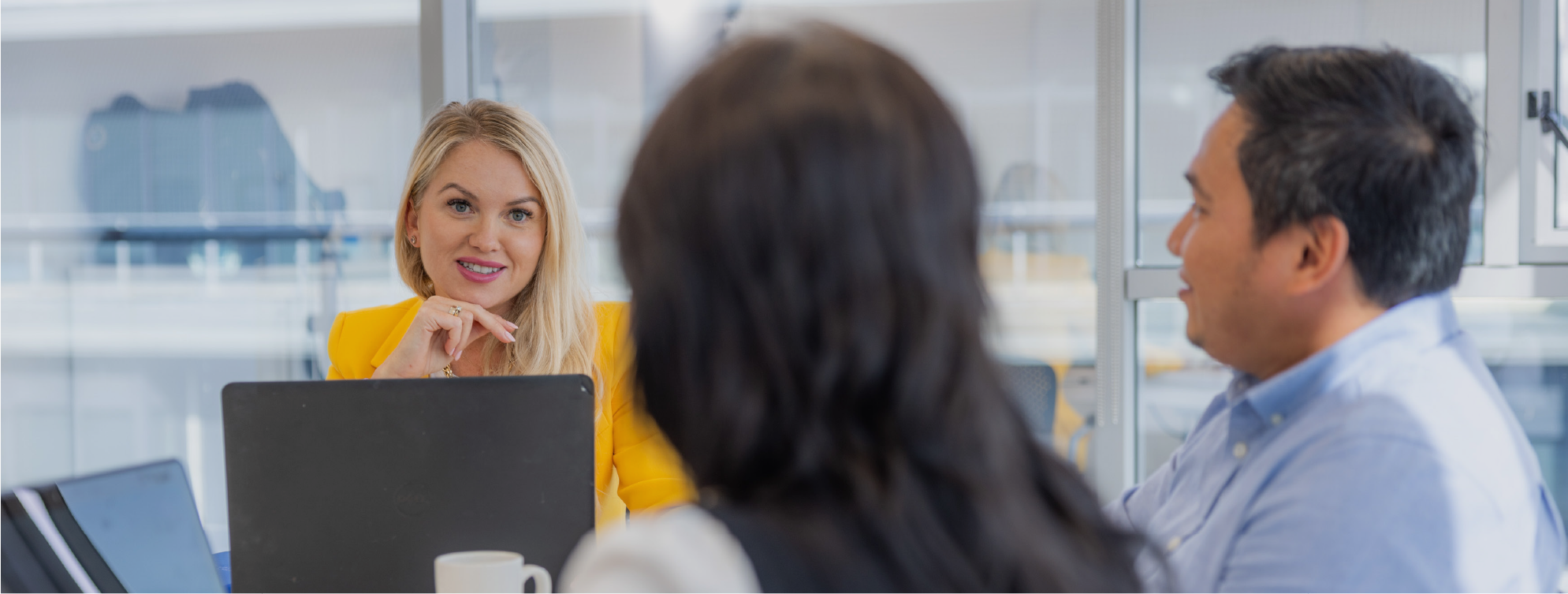 3 people , different gender and different ethicity in a meeting room with laptops.