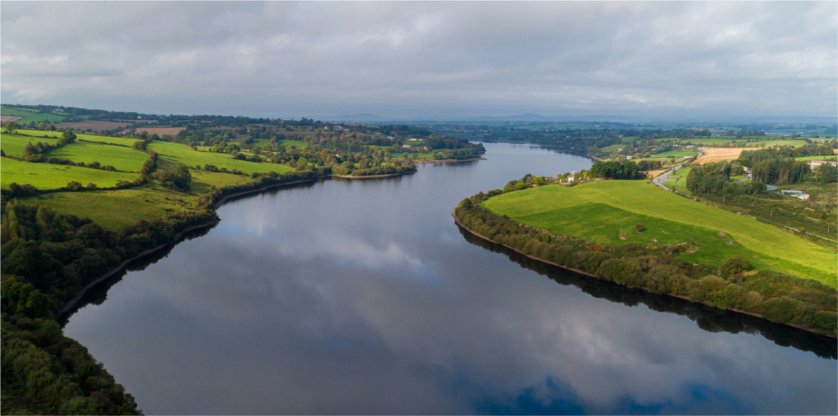 Meandering estuary on a calm day with green fields either side.