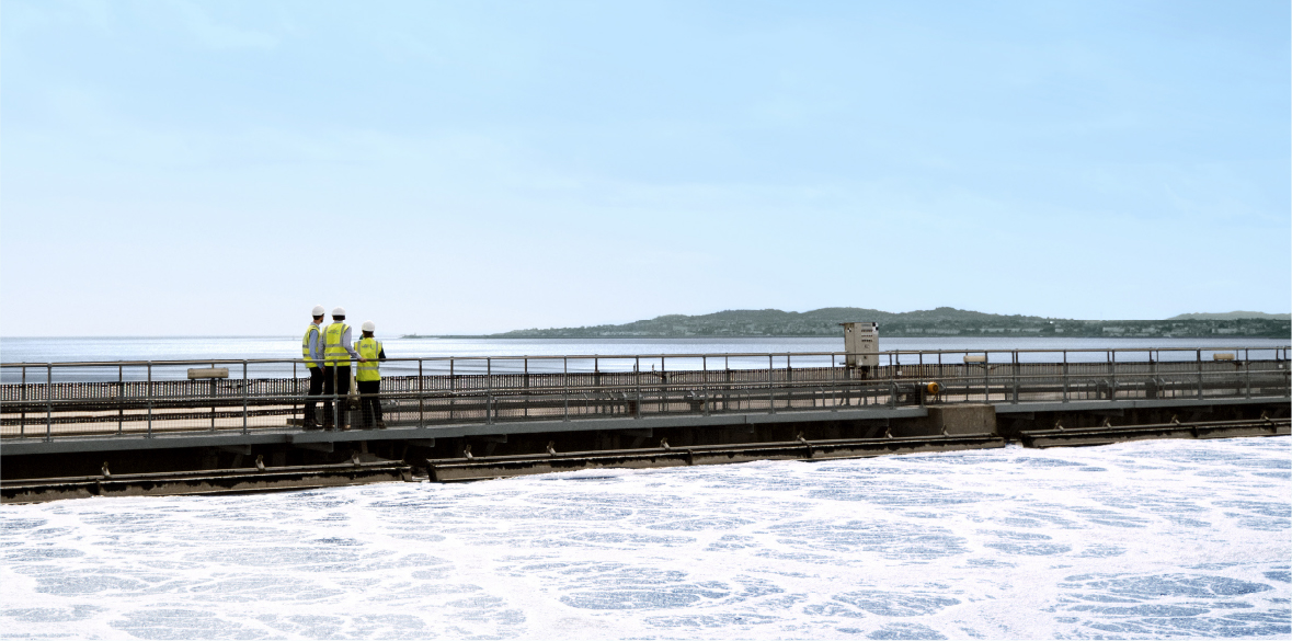 3 people in high-viz inspecting water plant.