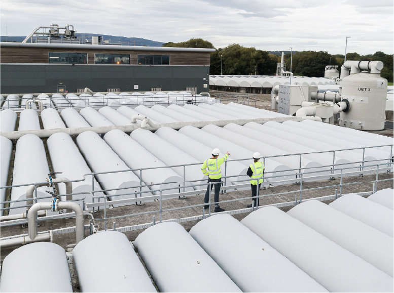 2 Uisce Eireann repsresentatives wearing PPE on walkway overviewing waterplant structure.