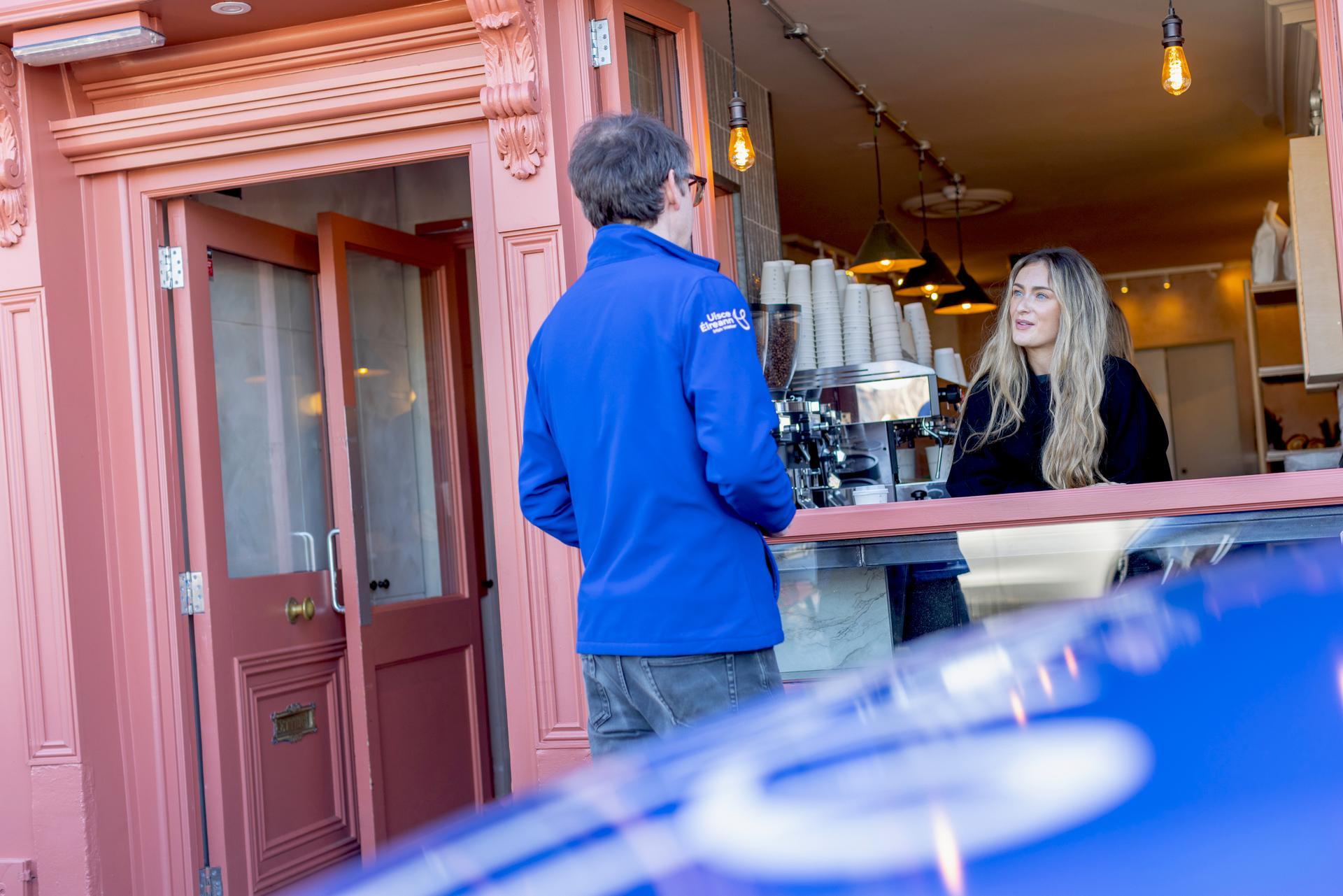 A barista making coffee in a coffee shop for an Uisce Éireann worker serving from a window