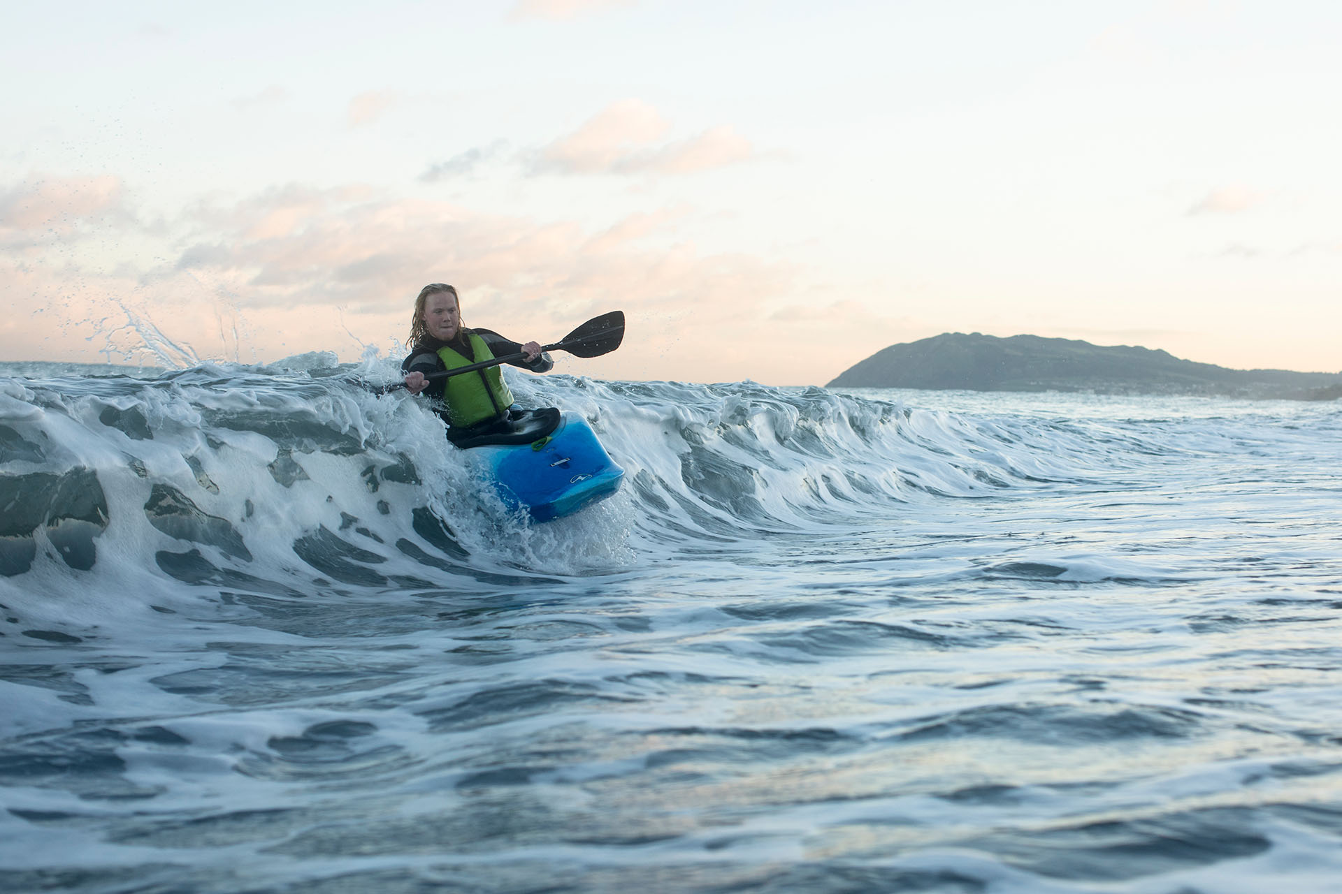 A person in a blue kayak riding a wave