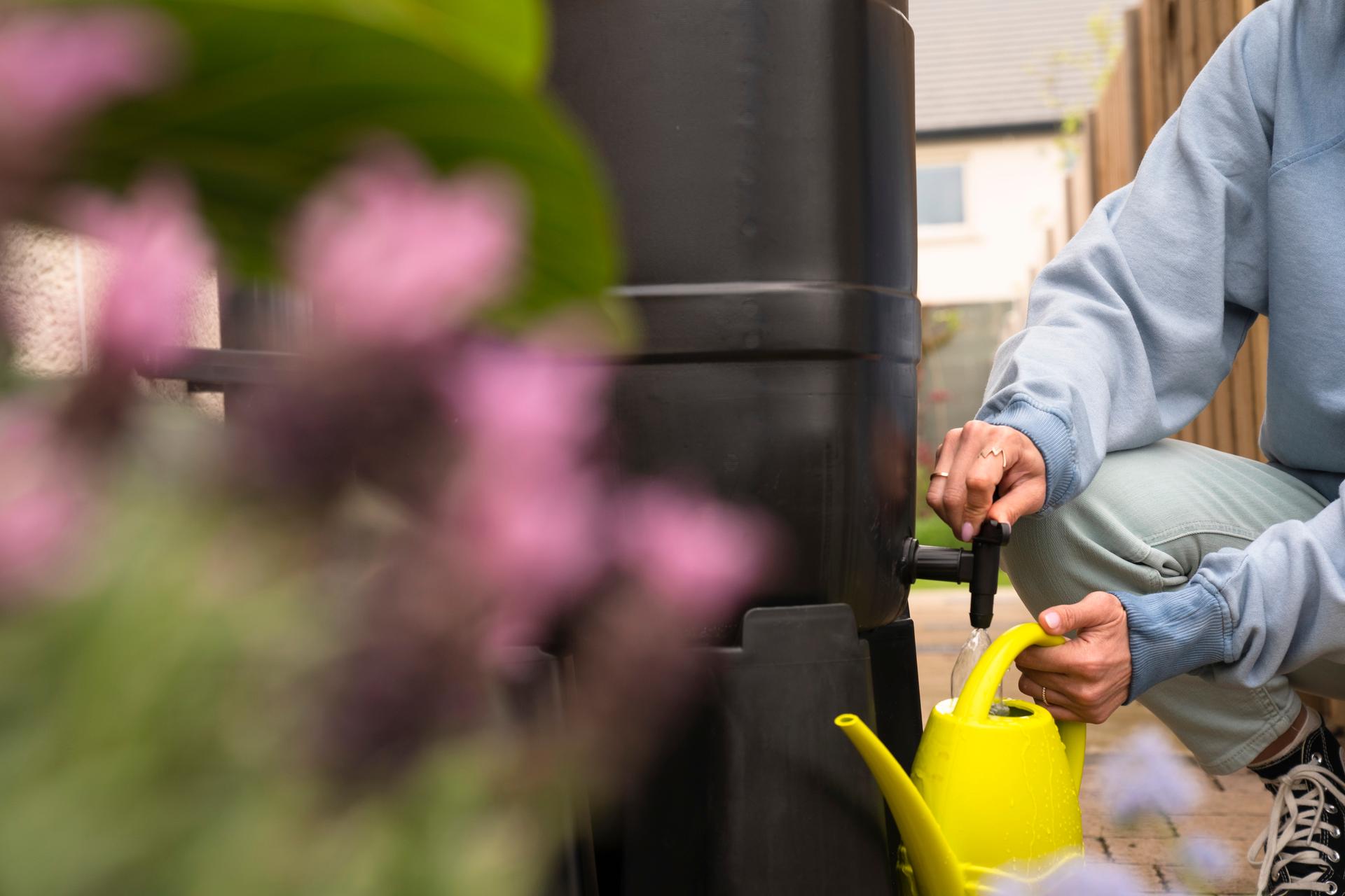 A person filling a watering can in a garden