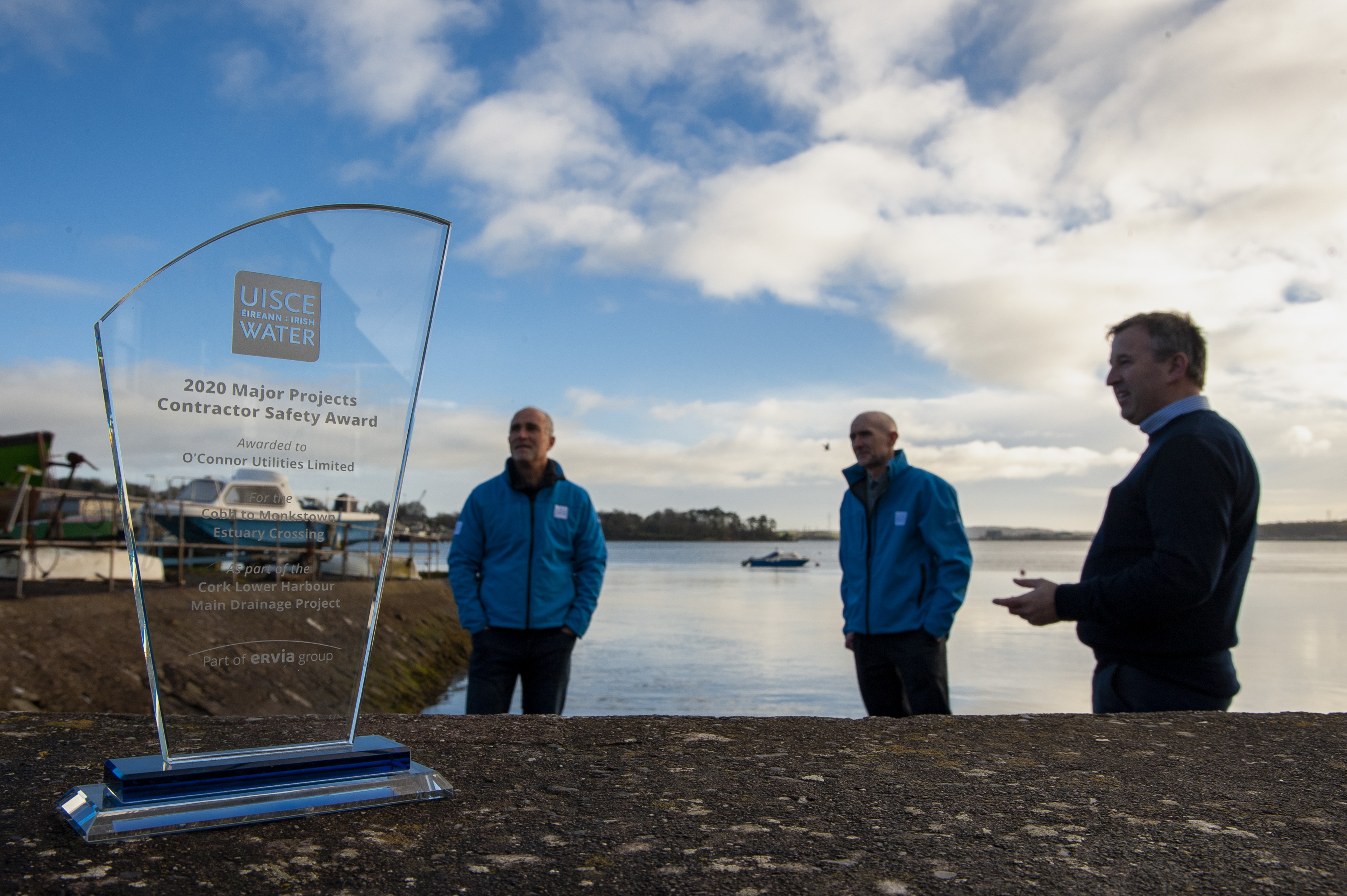 An glass trophy award near the docks with three people