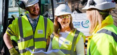 Three Uisce Éireann engineers holding site plans while smiling at eachother