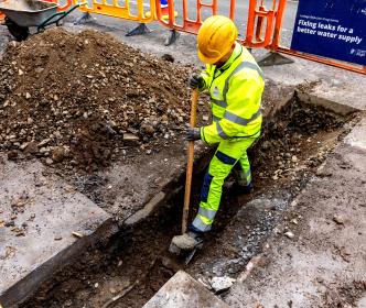 Worker digging a hole on a road