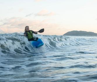A person in a blue kayak riding a wave
