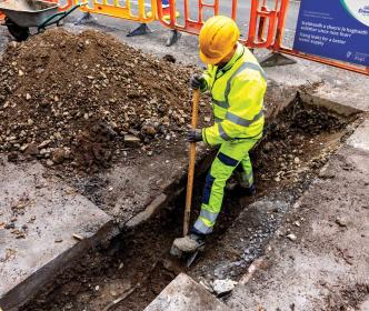 Worker digging a hole on a road